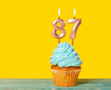 87 Numaralı Mumlu Doğum günü Pastası Sarı Arkaplanda.