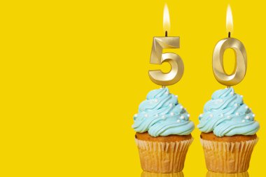 Sarı Arkaplanda 50 Numaralı Fotoğrafı Şekillendiren Mumlu Doğum günü Kekleri.