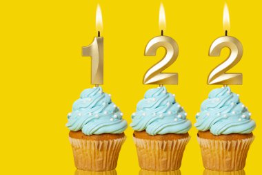 122 Numaralı Mum Işıklı Doğum Günü Kekleri Sarı Arkaplanda Fotoğraf.