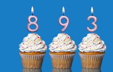 Birthday Cupcakes With Candles Lit Forming The Number 893 - Photo On Blue Background