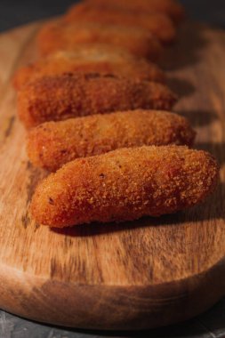 Lezzetli tipik İspanyol kroketlerinin dikey fotoğrafı. Tahta ve siyah arka planda ev yapımı İspanyol kroketleri. Tapas yemeği. Kara yemek..