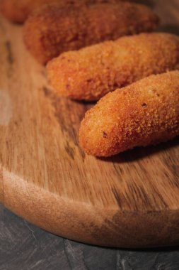 Lezzetli tipik İspanyol kroketlerinin dikey görüntüsü. Tahta ve siyah arka planda ev yapımı İspanyol kroketleri. Tapas yemeği. Kara yemek..