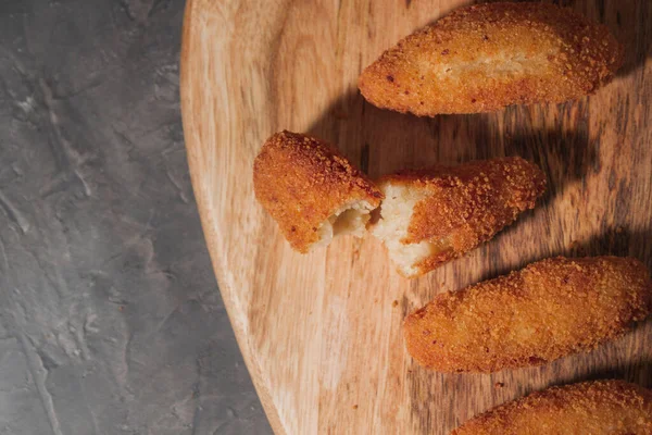 stock image Flat lay of delicious typical spanish croquetas with copy space. Homemade traditional spanish croquettes on a wood board and black background. Tapas food. Dark food.