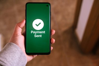 Kadının eli ekranda gönderilen ödemenin yazılı olduğu akıllı telefonu tutuyor. Mobil cihazlarla yapılan finansal işlemler kavramı. Yakın çekim fotoğrafı. Para transfer edildi. İnternetten alışveriş.