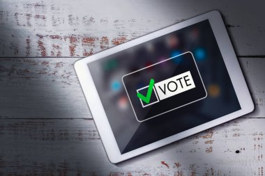 Tahta masadaki dijital tabletin en üst görüntüsü ve ekranda oylama. Politik kavram. Elektronik internet oylaması. Müşteri geribildirimi.