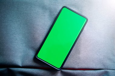 Akıllı telefon yeşil ekranının düz yatay fotoğrafı. Krom anahtar telefon ekranı dikey pozisyonda. Fotokopi alanı olan fotoğraf modeli. İnternet gibi şeyler. Yeni teknoloji kavramı.