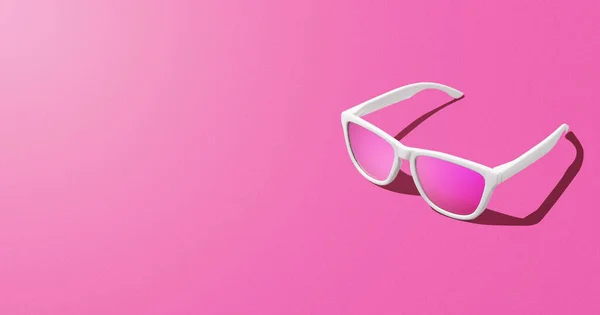 Banner of pink sunglasses over pink background and copy space. Studio shot.