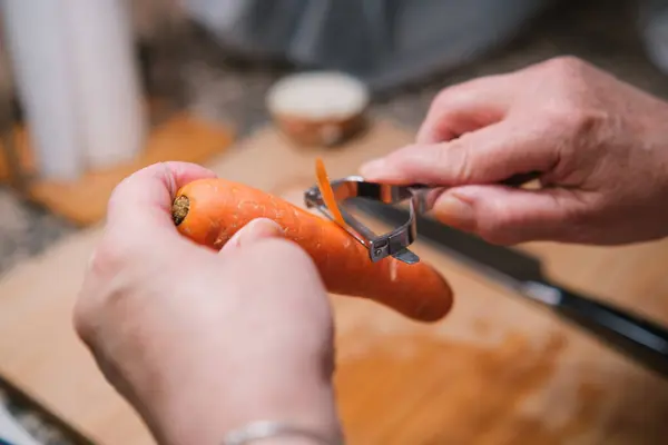 Κοντινό Πλάνο Χεριών Που Ξεφλουδίζουν Ένα Φρέσκο Καρότο Μαγειρεύοντας Υγιεινά — Φωτογραφία Αρχείου