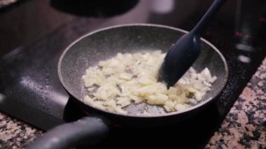Yakından çekilen videoda tavada zeytin yağıyla taze soğan pişiriliyor. Sağlıklı yemek pişirmek..