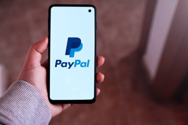 SPAIN - 23 Şubat 2024: Ekranda Paypal logosu olan akıllı telefonu tutan kadın. PayPal çevrimiçi ödeme göndermenin en popüler yoludur..
