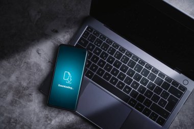 Dosyaları indirirken ya da telefona yazılım yüklerken akıllı telefon dizüstü bilgisayarda duruyordu. Veri desteği. Bulut deposu. Siber güvenlik.