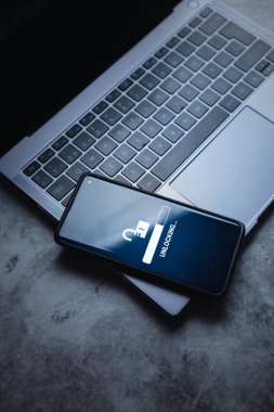 Akıllı telefonun ekrandaki kilit açma işlemiyle birlikte dizüstü bilgisayarda yatışı. Dijital aygıtın kilidini aç. Güvenlik koruması konsepti. Veri koruması.