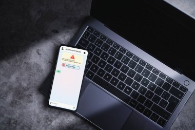 Dizüstü bilgisayarda yatan akıllı telefon şüpheli numara dolandırıcılığından mesaj alıyor. İstenmeyen isimsiz arama. Dolandırıcılık ve sahte telefon konsepti. Yabancıdan mesaj.