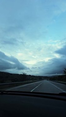 Bulutlu bir günde araba sürmek. Mavi ve fırtınalı gökyüzü. Yolda yağmur yağarken.