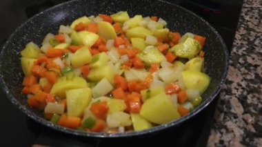 Renkli sebzeler karıştırılıyor. Taze patates, havuç ve tavada yeşil biber..