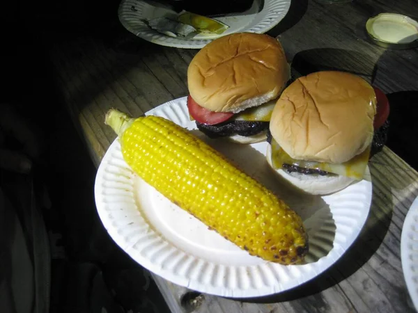 Cheeseburgers and Corn on a Paper Plate on Picnic Table. High quality photo