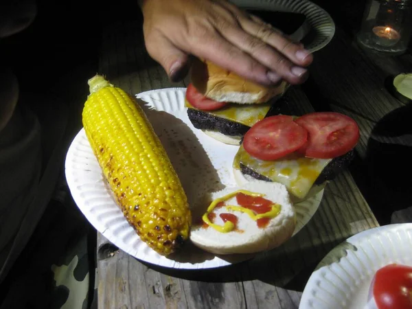 Cheeseburgers and Corn on a Paper Plate on Picnic Table. High quality photo