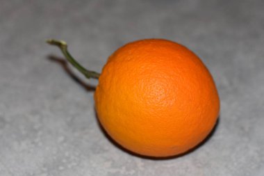 One Homegrown Orange with Stem Sitting on Counter. High quality photo
