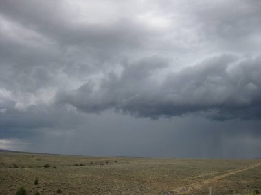 Dark Storm Clouds by Highway Pouring Rain Over Rolling Hills . High quality photo