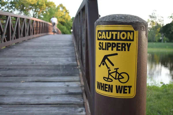 威斯康星州伯灵顿市福克斯河上的骑自行车的人在桥上湿警告标志时 小心滑倒 高质量的照片 — 图库照片