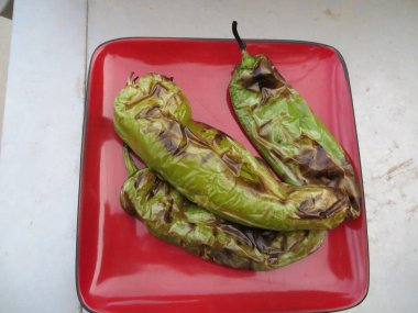 Kırmızı tabakta üç kavrulmuş Yeşil Hatch Chili Peppers. Yüksek kalite fotoğraf