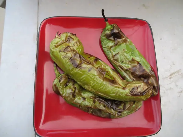 stock image Three Roasted Green Hatch Chili Peppers on a Red Plate . High quality photo