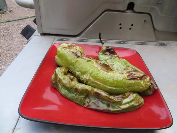 stock image Three Roasted Green Hatch Chili Peppers on a Red Plate . High quality photo