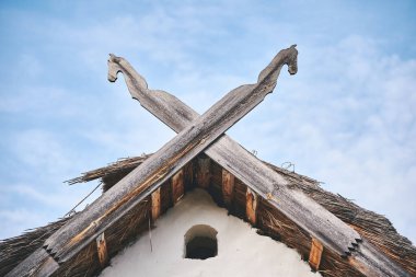 İskandinav tarzı ahşap süslemeler sazdan çatıda. Gökyüzüne karşı iki at kafası şeklinde ahşap süsleme.