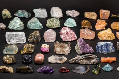 Koyu arkaplanda çeşitli taşlar ve jeolojik minerallerden oluşan bir koleksiyon. Renkli, çeşitli ham mineral taşları ve değerli taşlar.