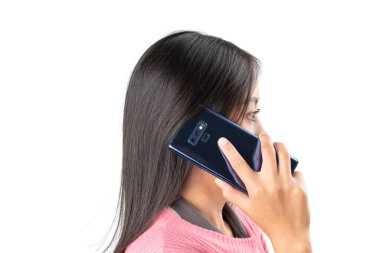 Pembe kazaklı bir kadının telefon görüşmesi yaparken kulağına mavi bir akıllı telefon tutarken yan görüntüsü. İletişim, teknoloji, bağlantı ve yaşam tarzı gibi konular için ideal.