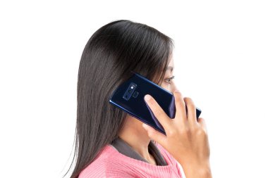 Pembe kazaklı bir kadının telefon görüşmesi yaparken kulağına mavi bir akıllı telefon tutarken yan görüntüsü. İletişim, teknoloji, bağlantı ve yaşam tarzı gibi konular için ideal.