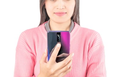 Pembe kazaklı bir kadının portresi gün batımının gradyan pembe akıllı telefonunda kayıyor. Teknoloji, yaşam tarzı, sosyal medya veya modern iletişim temaları için ideal.