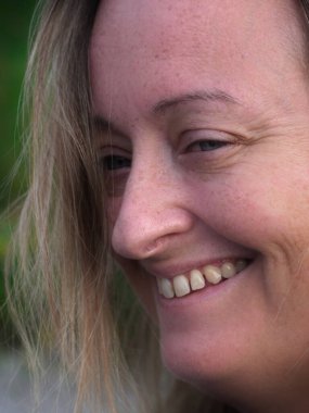 Gülümseyen sarışın, beyaz kadın portresi, yan görünüşü, hafif ışığı ve gölge etkisi var..