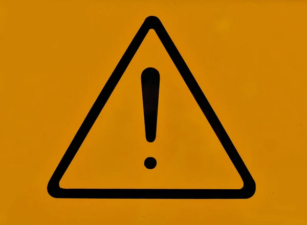 オレンジの背景の中央に感嘆符の付いた三角形 警告サイン — ストック写真