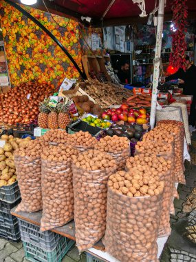 Arnavutluk 'un Tiran kentindeki bir açık hava pazarında meyve ve sebze satıcısı tezgahı. Patates, fındık ve çeşitli egzotik meyveler indirimde..