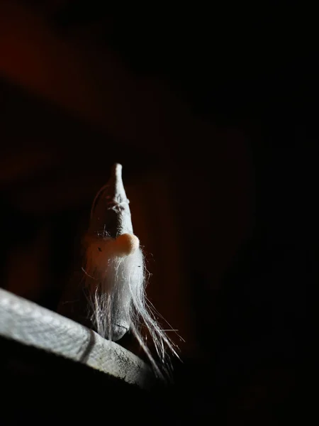Small character, with a big white beard and a big hat, at the edge of a chasm. Staging with light and shadow effect