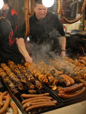Büyük bir ızgarada, Krakow noel pazarında hafif bulanık domuz boğumları, şişler ve sosisler..
