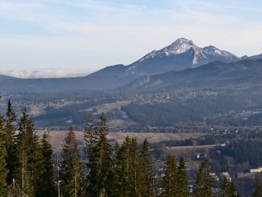 Large and panoramic view of a foggy valley in winter with mountains in background (Tatras mountains, Poland).