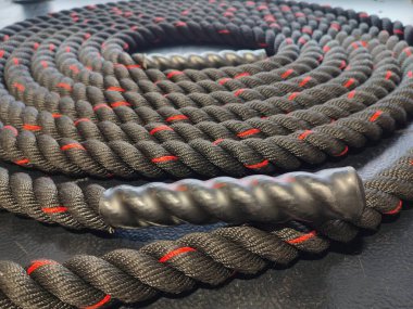 Slightly blurred battle rope, rolled on a gym floor. Focus on foreground.