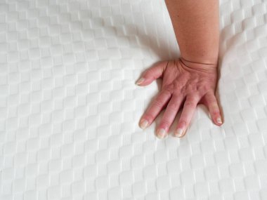 Yeni yatağın yumuşaklığını test eden bir kadın. Eli hafifçe batıyor.