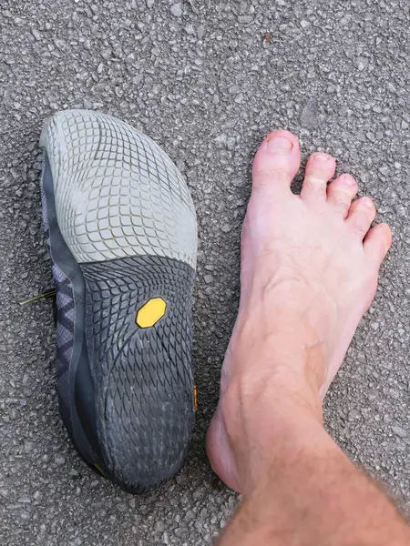 Man foot with spread toes close to a barefoot shoe. For the concept of walking barefoot or with barefoot shoes, to treat or prevent back pain.