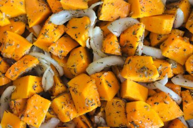 Soğan, provenal otlar ve yağ ile hazırlanmış balkabağı küplerinin yakın çekimi.