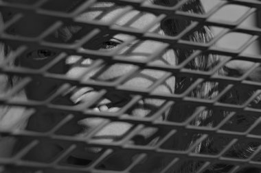 Örgü panelinin arkasına gizlenmiş bir kadının monokrom portresini kapat