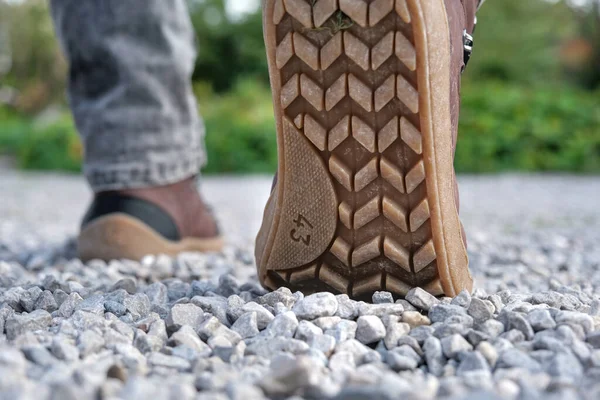 Close-up of the sole of a hiking boot, walking on gravel.