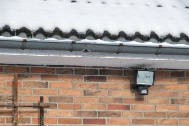 Karlı bir çatının altında, su sızdıran bir oluk..