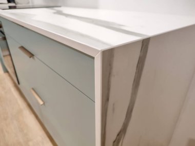 Mermer seramik tezgah, mavi-yeşil mutfak dolabında bronz saplı. Bir jartiyer kesiği ve mermer damar takibi gerçekleştirildi..