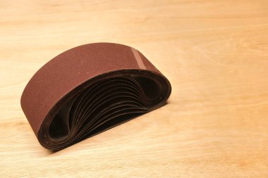 Sanding paper for belt sander on wood panel. clipart