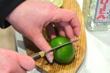 Close-up of a woman's hands cutting a lime on a wooden board. clipart