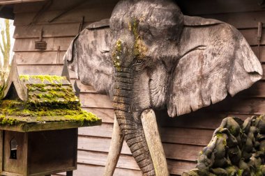 Brugelette, Belçika - 03 28 2024: Pairi Daiza zooloji parkı. Tahta bir tapınaktan sarkıtılmış, gerçekçi bir fil kafası heykeli. 