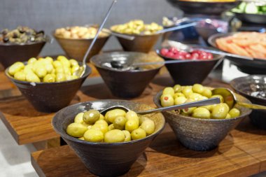 Kahvaltı büfesinde, kaselerde sunulan zeytinlerden oluşan bir seçim..